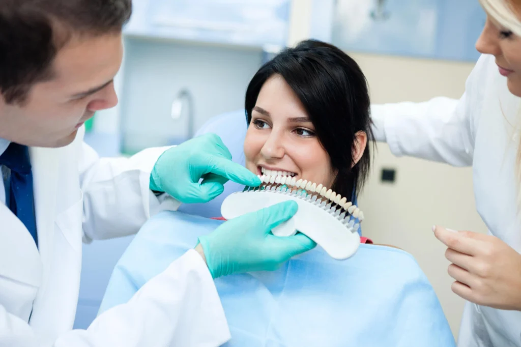 Girl comparing the shade of her teeth with a Cosmetic dentist Harrison NY